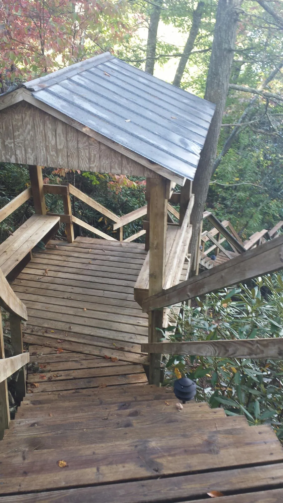 Metal roofed shelter over wooden steps on a wooded walkway — Skylight Repair & Installation work by our crew in Thompson